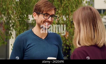 Couple of businessmen having corporate break outside office building. Two employees coworkers talking enthusiastic. Handsome man portrait. Happy employee facial expression. Stock Photo