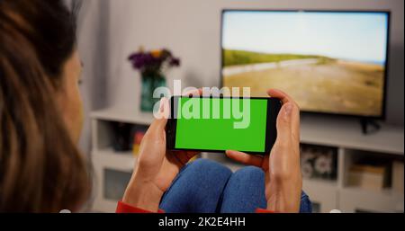 Woman Using Smartphone with Green Screen for Copy Space Close up Chroma Key Mockup. Scrolling Gestures. Girl watcing gadget green screen and touch display. Stock Photo