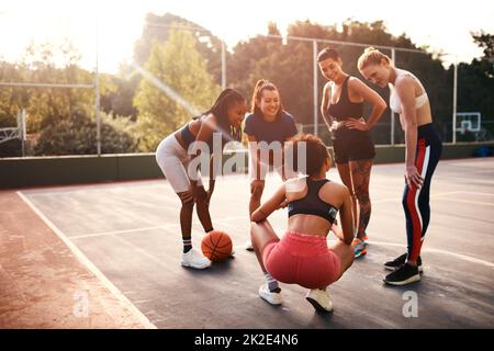 I think we should play like this. Cropped shot of a diverse group of friends getting ready to play a game of basketball together during the day. Stock Photo