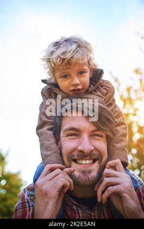Bonding with his beautiful boy. Cropped portrait of a handsome young man piggybacking his son outside during autumn. Stock Photo