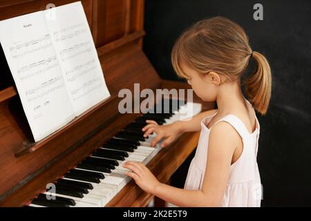 Practising for the recital. Cropped shot of a little girl playing the piano. Stock Photo