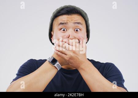 How did that happen. Studio shot of a young man looking shocked against a grey background. Stock Photo