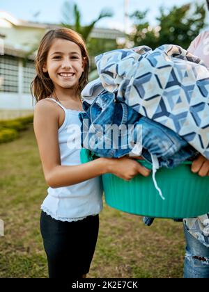 Happy to help mom out with the laundry. Portrait of a mother and daughter hanging up laundry together outside. Stock Photo