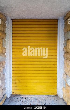 Bricks stone wall and closed yellow roll-up door Stock Photo