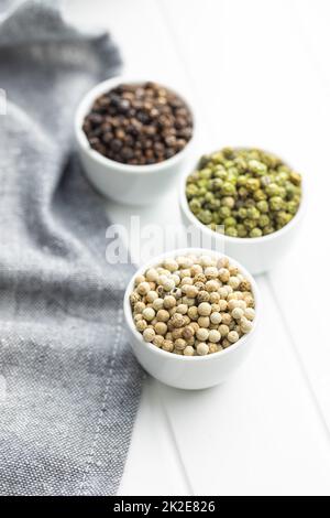 Three different types of pepper spice. Green, white and black peppercorn in bowls. Stock Photo