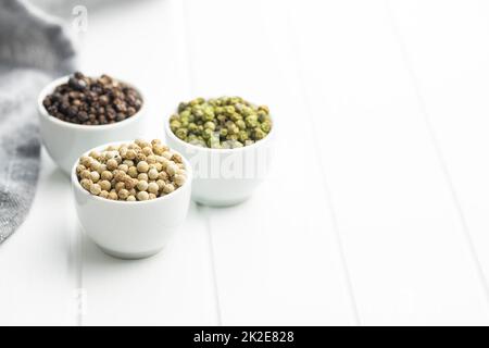 Three different types of pepper spice. Green, white and black peppercorn in bowls. Stock Photo