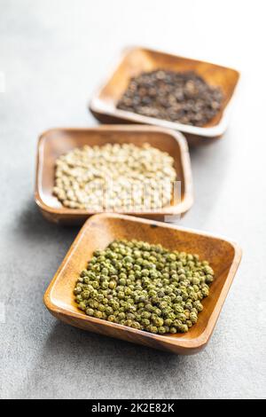 Three different types of pepper spice. Green, white and black peppercorn in bowls. Stock Photo