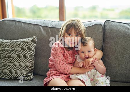 So happy to be a big sister. Portrait of a little girl bonding with her baby sister at home. Stock Photo
