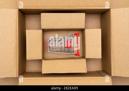 Shopping cart inside open rectangular cardboard box Stock Photo