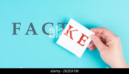 The word fact is standing on a paper, hand puts fake to the word, false and true information, media concept Stock Photo