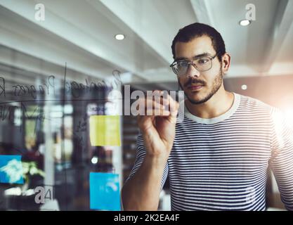 His plan is a work in progress. Cropped shot of a young male designer planning on a glass board. Stock Photo