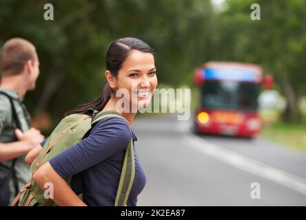They were still getting used to the roads. A beautiful young woman wearing a backpack while waiting for a bus with her husband. Stock Photo