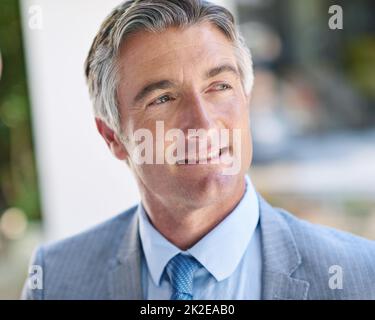 Hes a self-made man. Shot of a thoughtful-looking mature businessman standing outside. Stock Photo