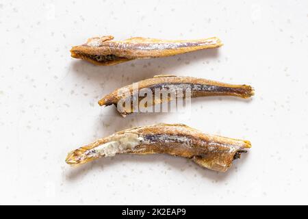 few dried anchovy fishes close up on gray Stock Photo