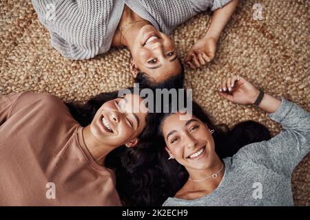Our circle of love. High angle shot of young sisters relaxing on the floor together at home. Stock Photo