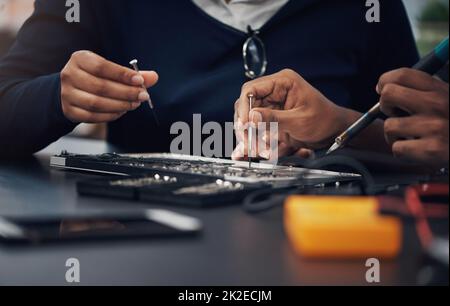 Whatevers wrong, theyll make it right. Shot of two technicians repairing a laptop together. Stock Photo