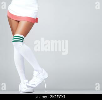 Showing my shyness through my feet. Close up of womans legs in a skirt and long socks with trainers on with copyspace. Stock Photo