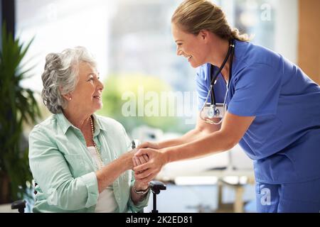 She has a great way with her patiends. Shot of a doctor shaking hands with a smiling senior woman sitting in a wheelchair. Stock Photo