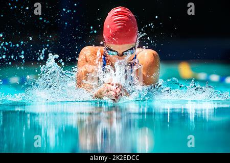 The hardest stroke in swimming.... Shot of a young female swimmer doing the butterfly stroke. Stock Photo