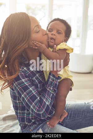 Showering her with kisses. Cropped shot of a young mother and her little baby girl at home. Stock Photo