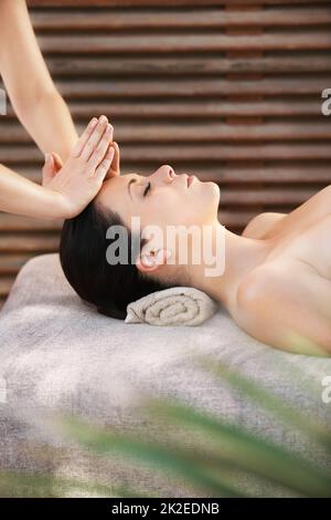 Embracing calmness. A young woman getting a face massage from a massage therapist. Stock Photo