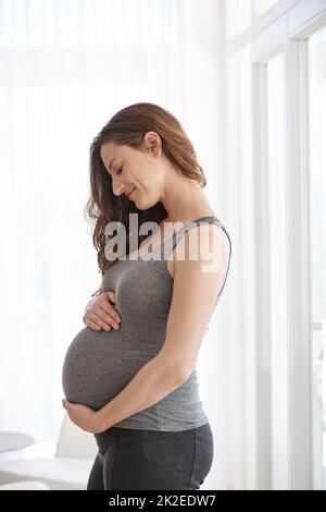 Showing her unborn baby some love. Cropped shot of a young pregnant woman standing in her home. Stock Photo