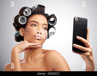 Woman in hair curlers taking funny selfie on mobile while cooking in the  kitchen Stock Photo - Alamy