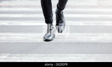 Even small steps can lead to greatness. Shot of an unrecognizable businessman crossing the street in the city. Stock Photo