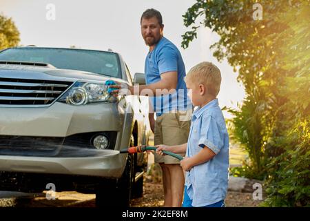 He may be young but hes still very helpful. Cropped shot of a father and son washing a car together. Stock Photo