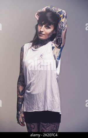 Sweet and sassy. A cropped studio portrait of a tattooed young woman. Stock Photo