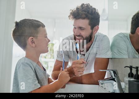 Got to take care of our teeth. Shot of a father and his little son brushing their teeth together in the bathroom at home. Stock Photo