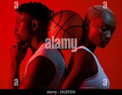 Its the support that gets us through it. Red filtered shot of a sporty young man and woman posing with a basketball in between them. Stock Photo