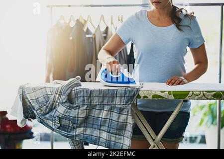 Getting those wrinkles out. Shot of an unrecognizable woman doing her daily chores at home. Stock Photo