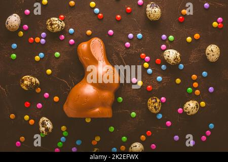 Delicious chocolate easter eggs, bunny and sweets on dark brown background Stock Photo
