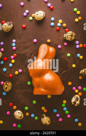 Delicious chocolate easter eggs, bunny and sweets on dark brown background Stock Photo