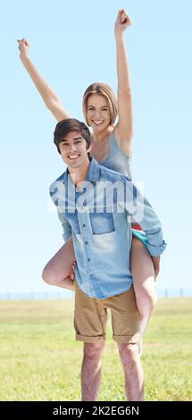 Ahhhhh, young love. A young man piggybacking his girlfriend in the outdoors. Stock Photo