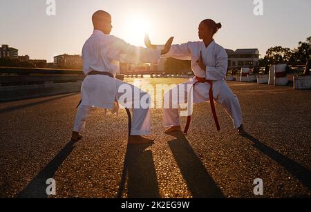 Ready to spar. Two sportspeople facing off and practicing their karate while wearing gi. Stock Photo