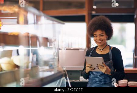 Being an entrepreneur is both challenging and exciting. Portrait of a young entrepreneur using a digital tablet in her business. Stock Photo