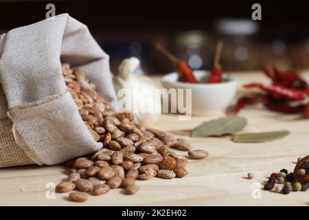 Burlap Sack of Pinto Beans on Table with Spices in Background Stock Photo