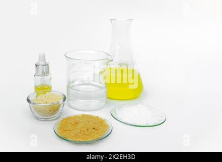 Cosmetic chemicals ingredient on white laboratory table. Carnauba Wax Flakes, Candelilla Wax, Microcrystalline wax, Nickle chloride liquid, alcohol Stock Photo