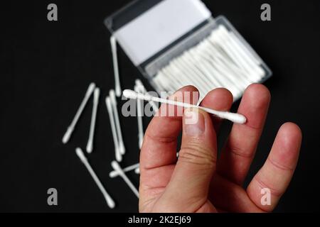 one hand holding cotton ear cleaning litter on black background Stock Photo