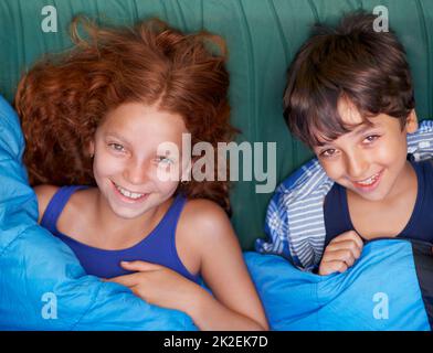 Relaxing in their tent. Portrait of a young brother and sister lying down and smiling. Stock Photo