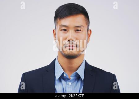 Hes a straight-faced businessman. Studio portrait of a handsome young businessman posing expressionless against a grey background. Stock Photo