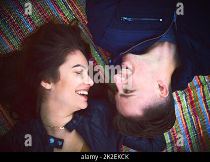 Its a day booked for love. Shot of a happy young couple lying on a blanket outdoors. Stock Photo