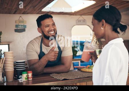 let me tell you my story. Shot of a woman buying and drinking a smoothie from a food truck. Stock Photo