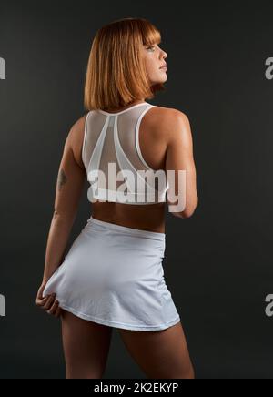 Dressed to win. Rearview shot of a woman wearing sports clothing against a dark background. Stock Photo