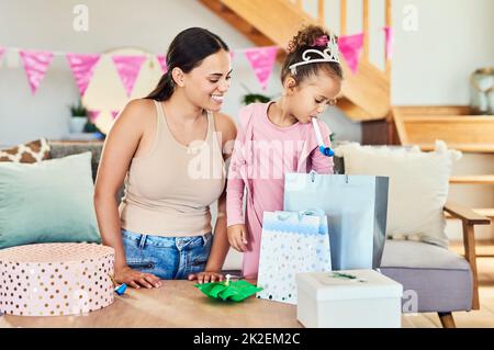 Are these all for me. Shot of a little girl opening her presents during a birthday party at home. Stock Photo