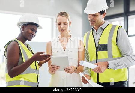 Manager on a digital tablet with her construction team in her modern office on the work site. Happy, professional and industry workers reading and Stock Photo