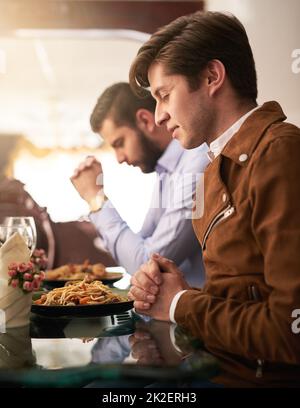 Giving thanks for the food. Cropped shot of two young brothers saying grace during a family dinner at home. Stock Photo