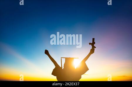 The silhouette of Student Celebrating Graduation watching the sunlight Stock Photo